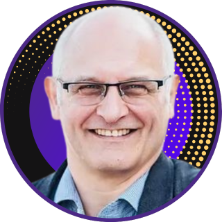 Profilbild von Philipp Fuchs, ein freundlich lächelnder Mann mit einer Brille, eingerahmt von einem kreisförmigen, violetten Hintergrund mit goldenen Punkten, repräsentiert als Coach in der Coaching Community von PurposeCoach®